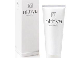 Cutie albă Crema de corp cu colagen Nithya Body Creme Fluid și tub alb cu cremă lângă cutie, pe fundal alb. Textul "Nithya Body Creme Fluid" este vizibil pe cutie și tub.